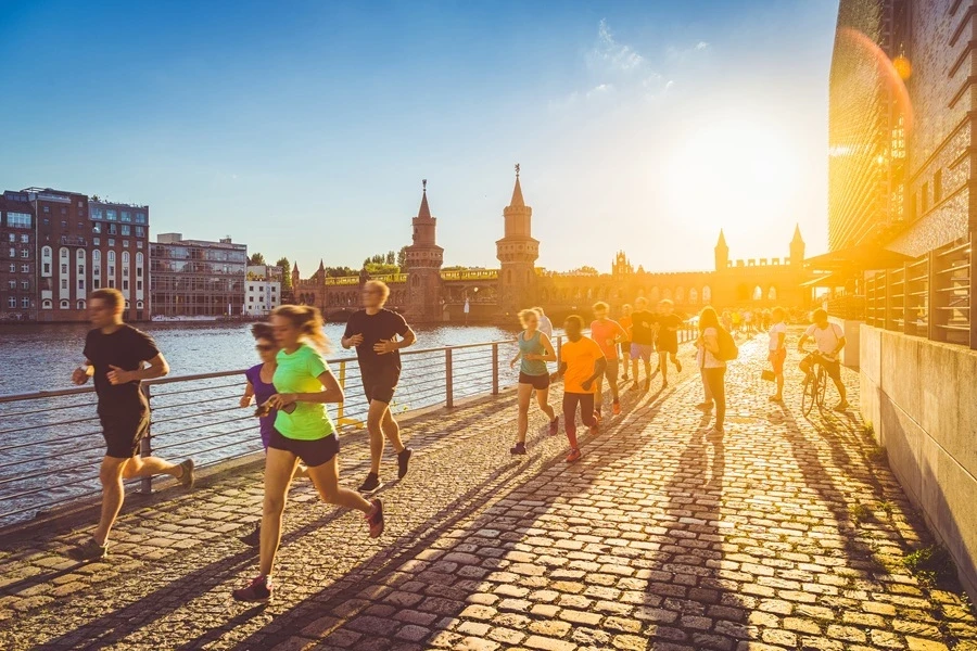 Runners jogging along a riverside path at sunset Runners jogging along a riverside path at sunset