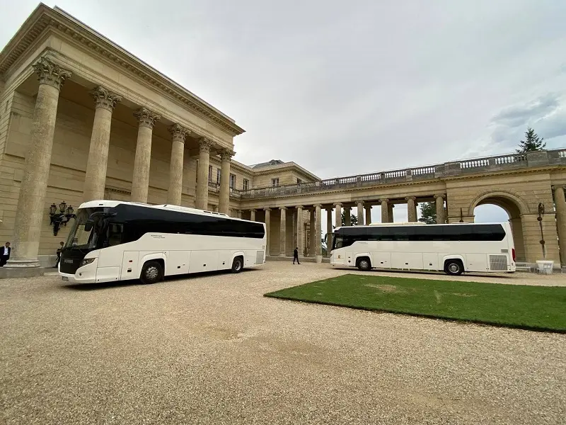 Charter bus Paris service showcased with two modern white buses parked in front of an opulent historical building, offering a sophisticated travel experience for city tours and group transportation in Paris.